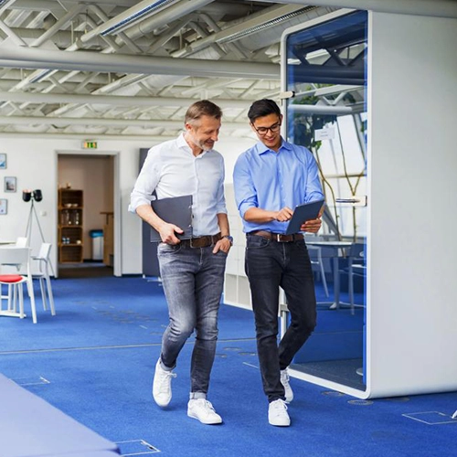 Zwei Männer im modernen Büro und Casual-Bekleidung besprechen Unterlagen.