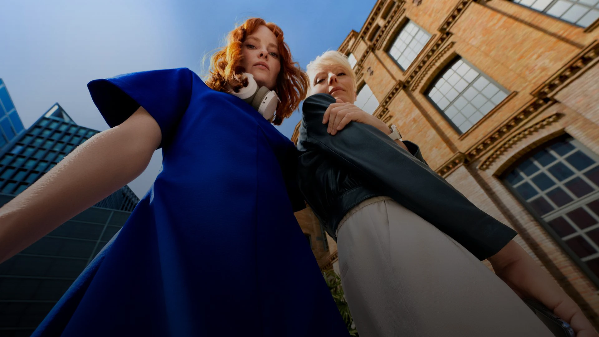 Zwei Männer essen Eis bei schönem Wetter; einer hält ein Smartphone, der andere sitzt auf einem Auto.