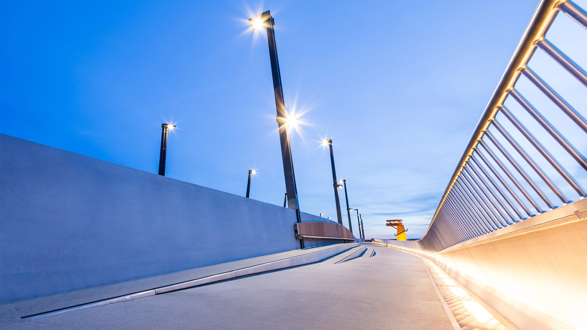 Street with four lanterns; barrier on the right.